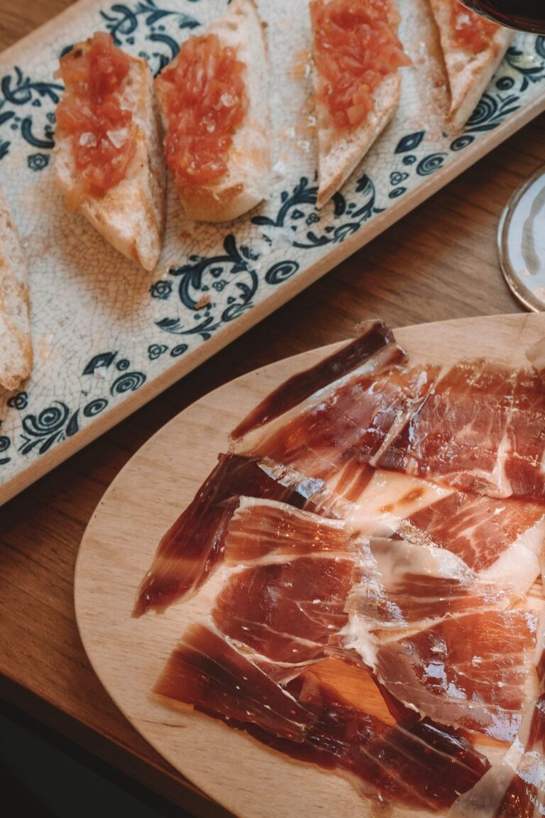 Plato de jamón loncheado junto a tostadas de pan con tomate